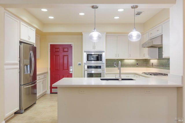 kitchen featuring visible vents, a sink, a peninsula, under cabinet range hood, and stainless steel appliances