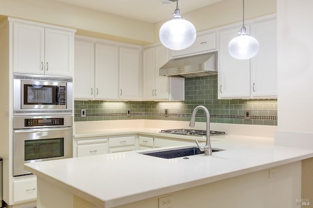 kitchen featuring tasteful backsplash, stainless steel appliances, a peninsula, and under cabinet range hood