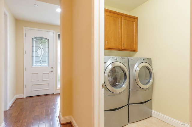 washroom with baseboards, light wood-type flooring, cabinet space, and washing machine and clothes dryer