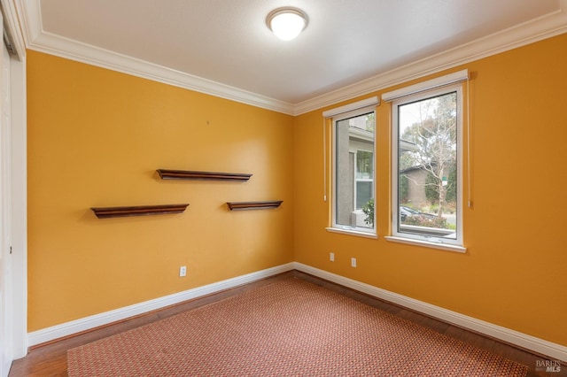 spare room featuring crown molding, baseboards, and wood finished floors