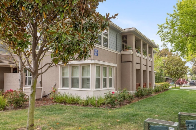 view of side of property featuring stucco siding and a yard