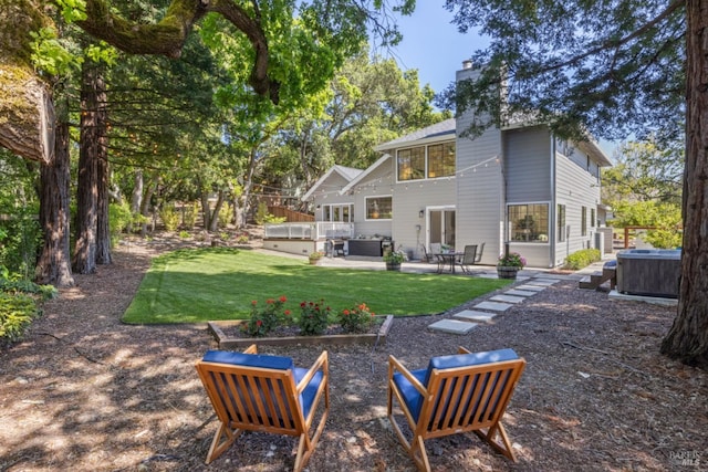 back of house with a hot tub, outdoor lounge area, a chimney, a patio area, and a yard