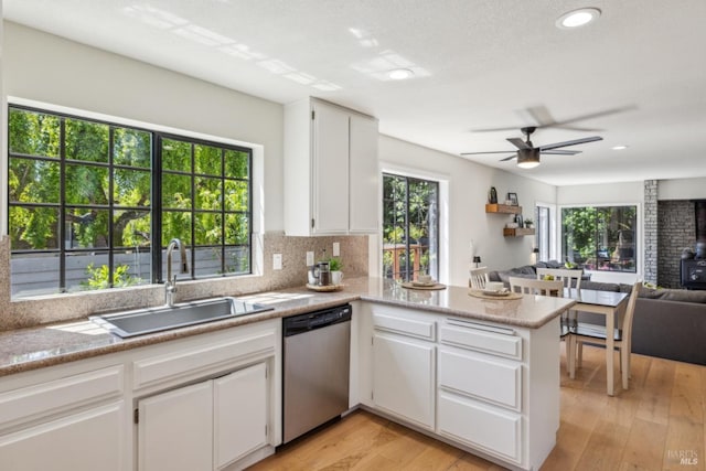 kitchen featuring ceiling fan, dishwasher, a sink, a peninsula, and open floor plan