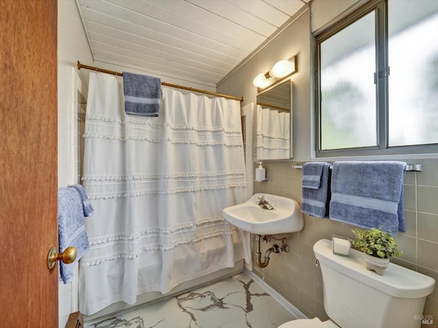 full bath with a sink, toilet, marble finish floor, tile walls, and wood ceiling