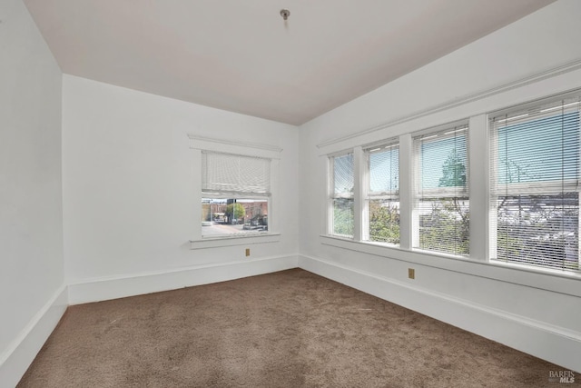 empty room with baseboards and dark carpet