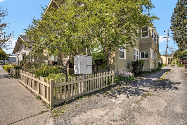 view of side of property featuring fence and mail area
