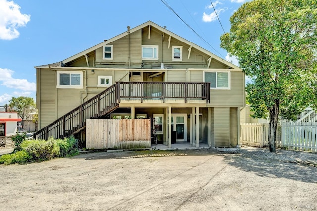 rear view of property featuring a wooden deck, fence, and stairway