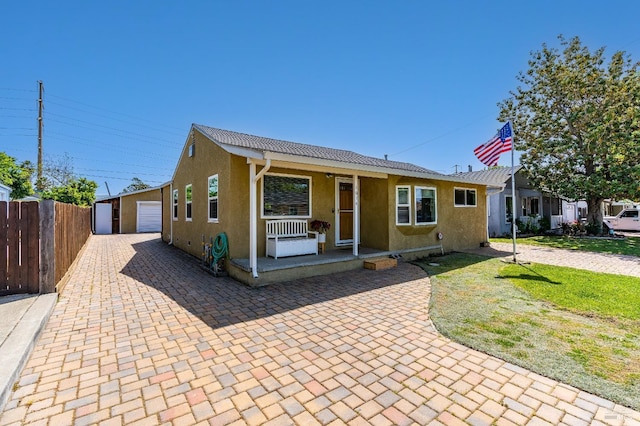 1034 Caldwell Ave, Vallejo, CA 94591 - view of front of property with fence, a detached garage, stucco siding, a porch, and an outdoor structure