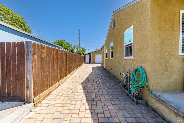 1034 Caldwell Ave, Vallejo, CA 94591 - view of side of home with fence, a detached garage, an outdoor structure, and stucco siding