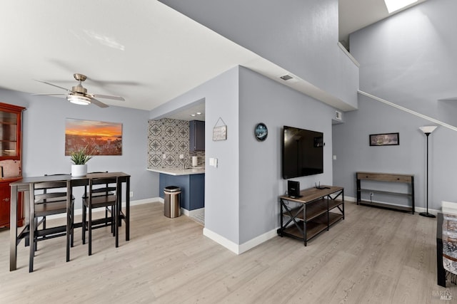 living room with a ceiling fan, baseboards, and wood finished floors