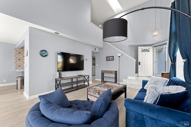 living area featuring baseboards, visible vents, wood finished floors, and a high ceiling