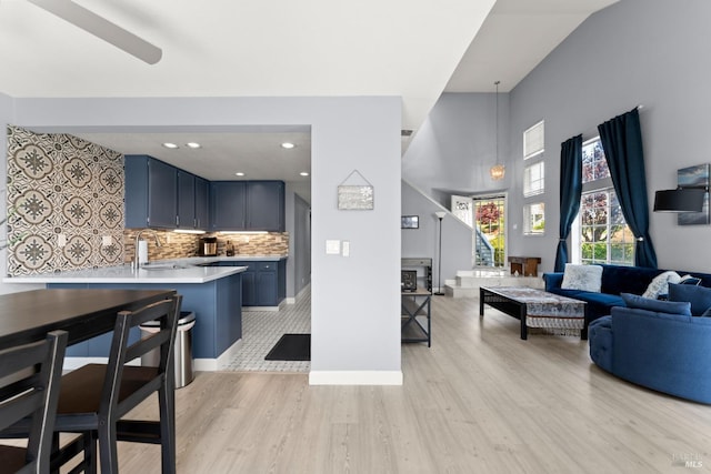 living room featuring baseboards, light wood-style flooring, and a high ceiling