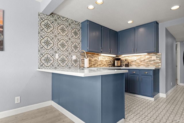 kitchen featuring a peninsula, blue cabinetry, and tasteful backsplash