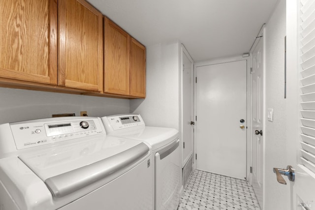 clothes washing area with cabinet space, washing machine and dryer, and light floors