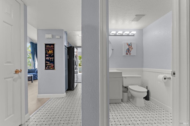 bathroom with a textured ceiling, visible vents, tile patterned floors, vanity, and toilet