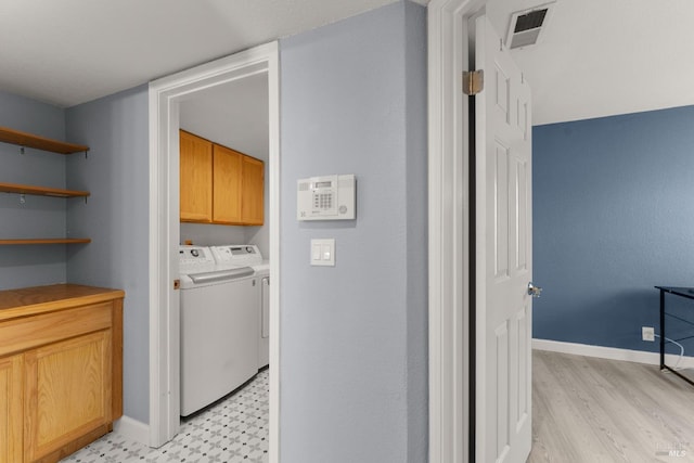 laundry area featuring washing machine and clothes dryer, visible vents, cabinet space, baseboards, and light floors