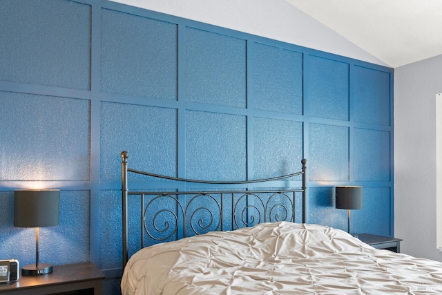 bedroom featuring lofted ceiling and a decorative wall