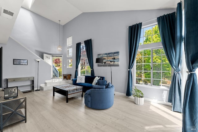 living area featuring visible vents, wood finished floors, stairway, high vaulted ceiling, and baseboards