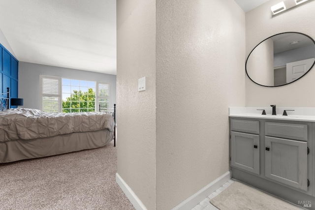 ensuite bathroom with vanity, a textured wall, baseboards, and ensuite bath