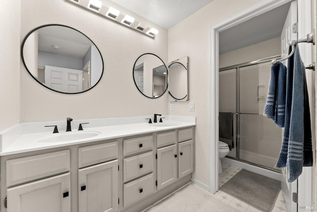 bathroom featuring a sink, toilet, and a shower stall