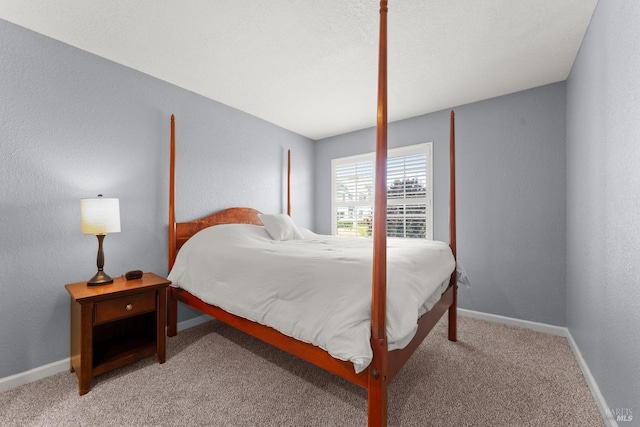 bedroom with baseboards, a textured wall, and light colored carpet
