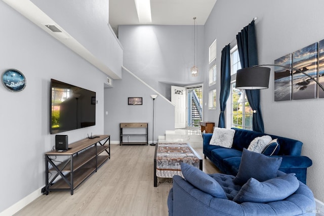 living room with visible vents, a high ceiling, baseboards, and wood finished floors