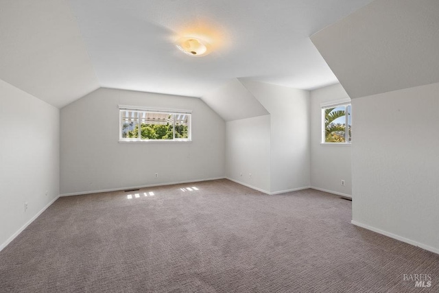 bonus room featuring carpet floors, visible vents, baseboards, and lofted ceiling