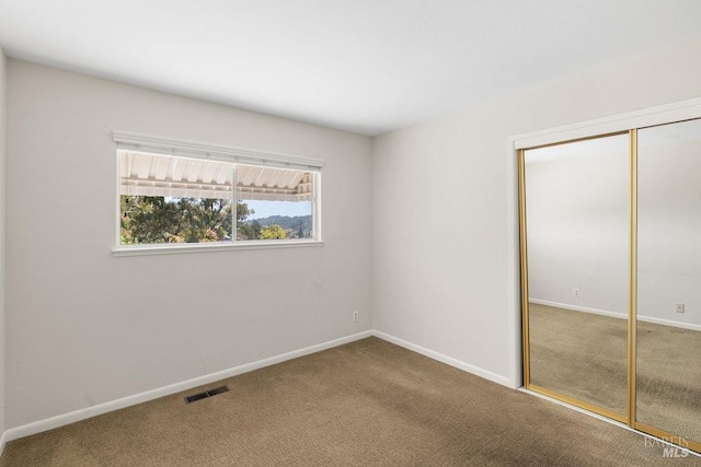 unfurnished bedroom featuring carpet flooring, baseboards, visible vents, and a closet