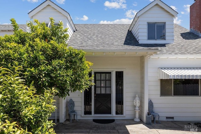 view of exterior entry featuring a shingled roof and visible vents