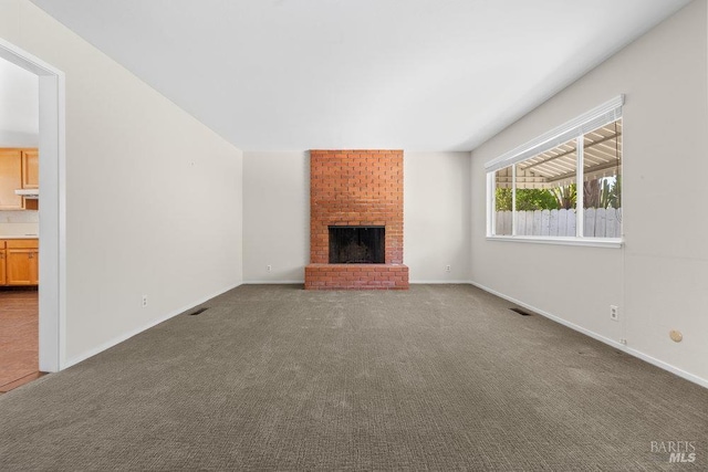 unfurnished living room with baseboards, carpet flooring, and a brick fireplace