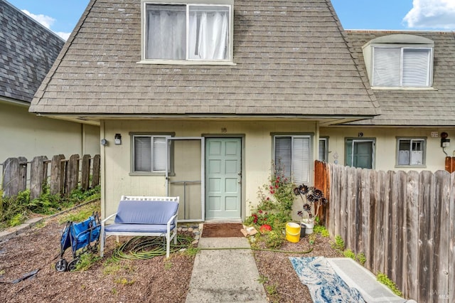 doorway to property with a shingled roof and fence
