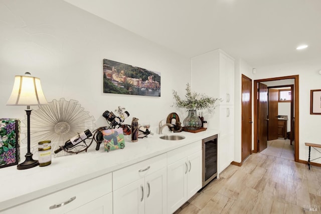 bar featuring beverage cooler, baseboards, recessed lighting, light wood-type flooring, and a sink