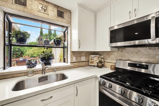 kitchen featuring a sink, light countertops, stainless steel appliances, white cabinetry, and backsplash