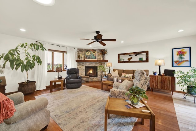 living area featuring a fireplace, a ceiling fan, recessed lighting, and light wood-style flooring