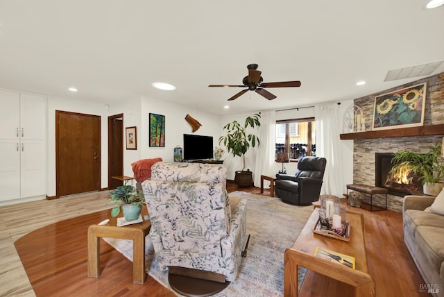 living area featuring ceiling fan, visible vents, light wood-style floors, and a fireplace