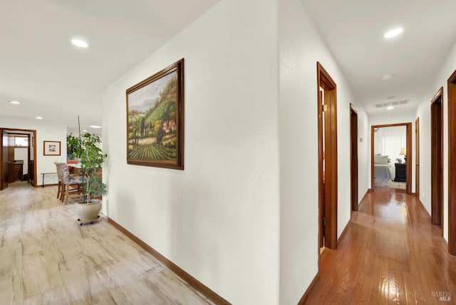 hallway with recessed lighting, baseboards, visible vents, and light wood-type flooring