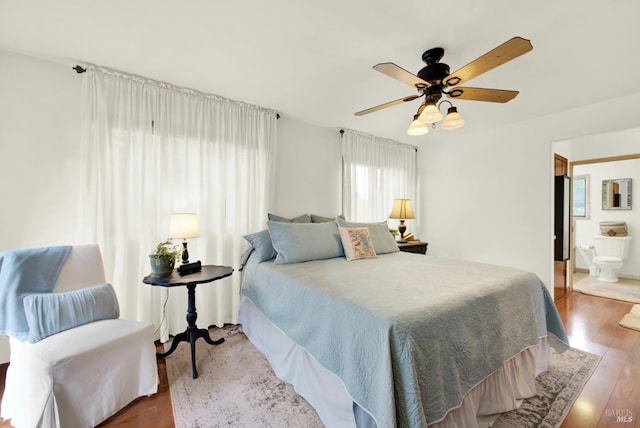 bedroom with ceiling fan, wood finished floors, and ensuite bath