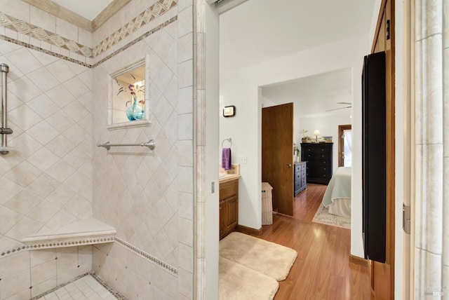 bathroom with connected bathroom, a tile shower, wood finished floors, and vanity