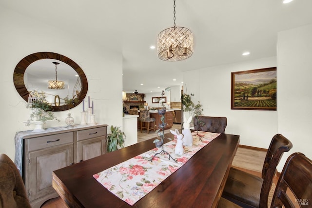 dining area with an inviting chandelier, a fireplace, light wood-style floors, baseboards, and recessed lighting