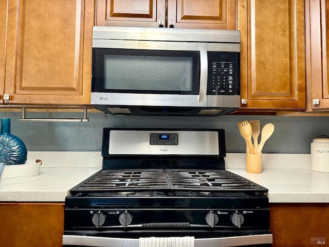 details with stainless steel appliances, light stone counters, and brown cabinetry