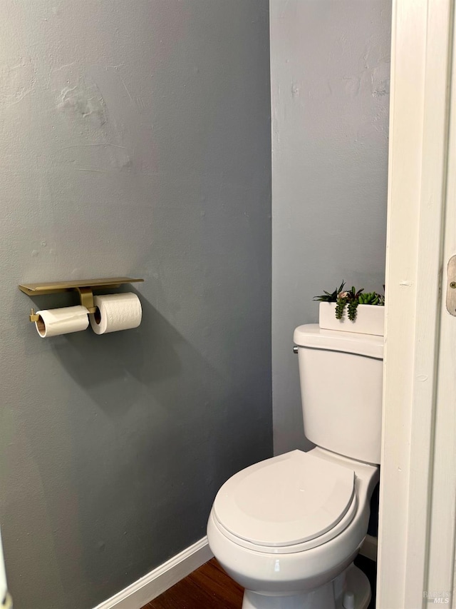 bathroom featuring toilet, baseboards, and wood finished floors