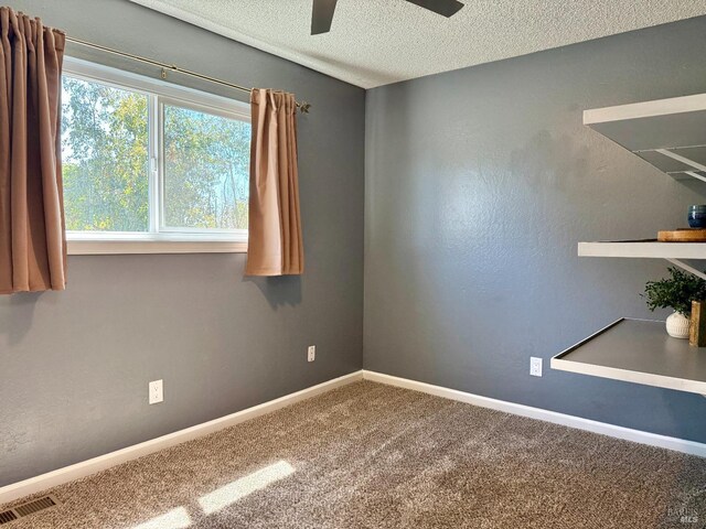 carpeted empty room featuring baseboards, a ceiling fan, a textured ceiling, and visible vents