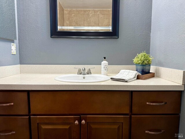 bathroom with a textured wall and vanity