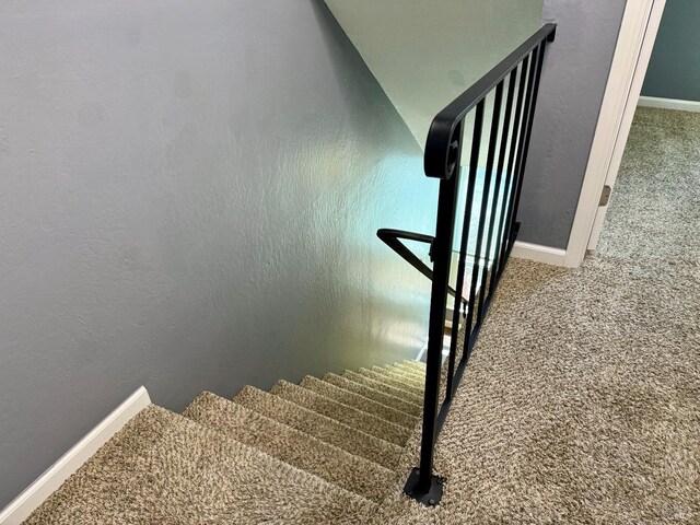 stairs featuring carpet floors, baseboards, and a textured wall