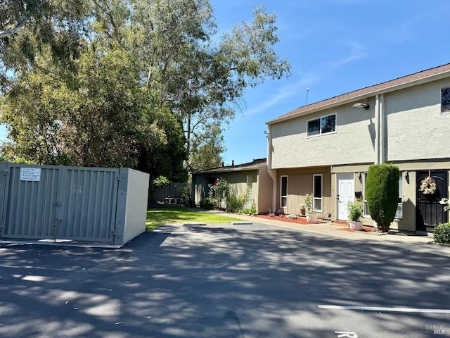 exterior space with a gate, stucco siding, and fence