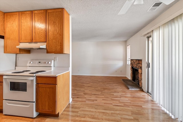kitchen with electric range, visible vents, light countertops, light wood-style floors, and under cabinet range hood