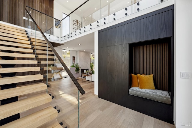 stairs with a high ceiling and wood finished floors