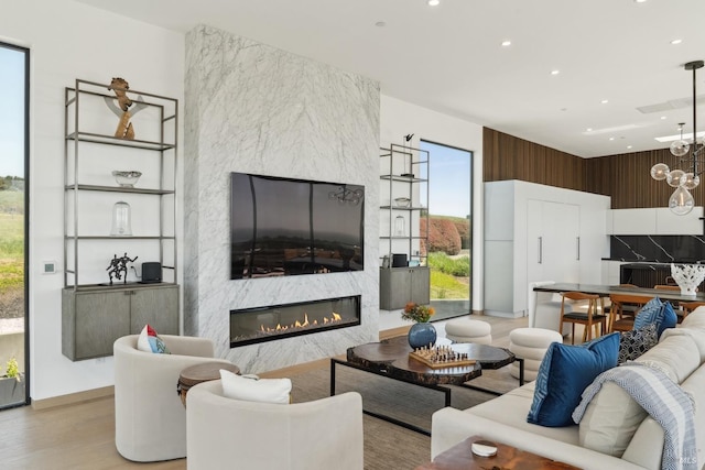 living area with a fireplace, a chandelier, recessed lighting, wood finished floors, and visible vents