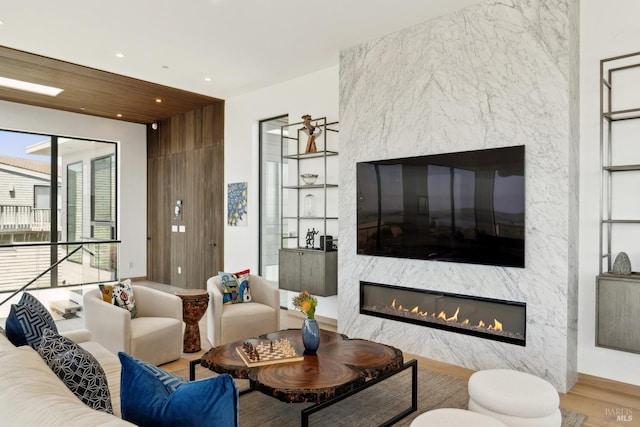 living area with recessed lighting, a high end fireplace, and wood finished floors