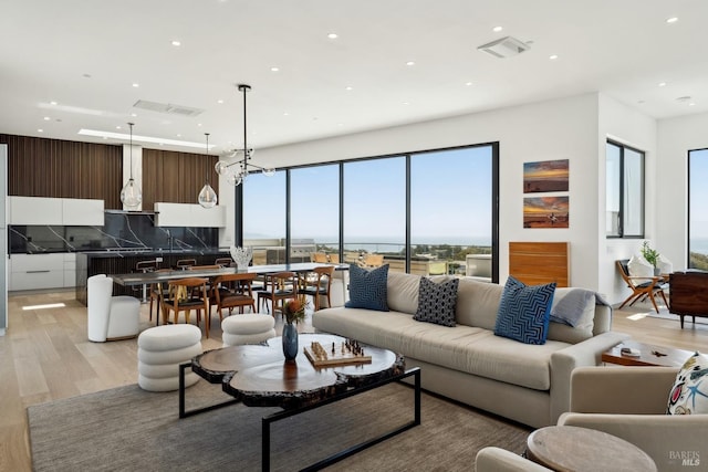 living room with recessed lighting, light wood finished floors, and visible vents